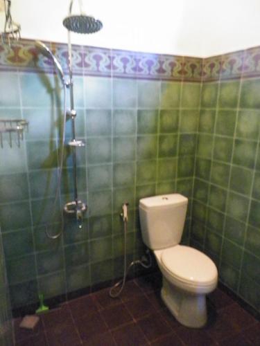 a green tiled bathroom with a toilet and a shower at Rumah Sawah in Yogyakarta