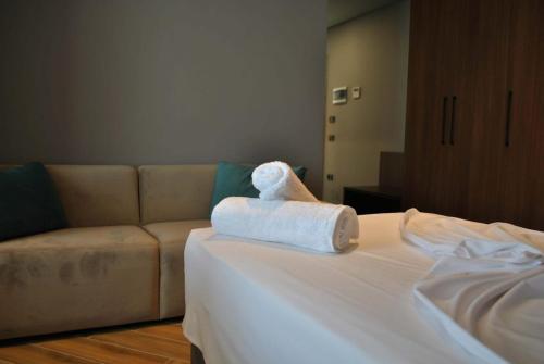 een witte handdoek op een bed met een bank bij Twin Towers Hotel City & Beach Resort in Shëngjin
