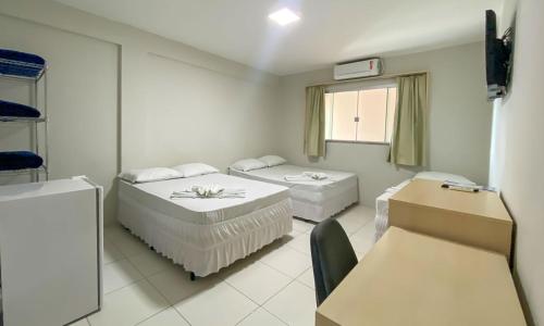 Habitación blanca con 2 camas y ventana en CENTER PLAZA HOTEL en Cristalina