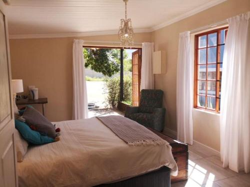 The Nelsbells Cottage في كلارينس: غرفة نوم بها سرير وكرسي ونافذة