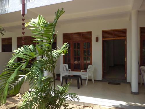 a porch of a house with chairs and a table at Celestial Inn in Mirissa