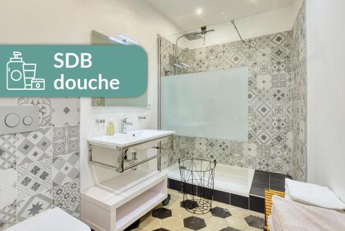 La salle de bains blanche est pourvue d'un lavabo et d'une douche. dans l'établissement Appartement Saint Jean, à Lyon