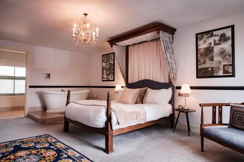 1 dormitorio con cama, bañera y silla en The Bower Inn, en Bridgwater