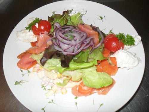 a white plate with a salad with tomatoes and onions at Der Dorfwirt in Rechberg
