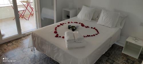 ein weißes Bett mit einem Herz aus Rosen in der Unterkunft VACACIONES DUQUE GALEY in Punta Umbría
