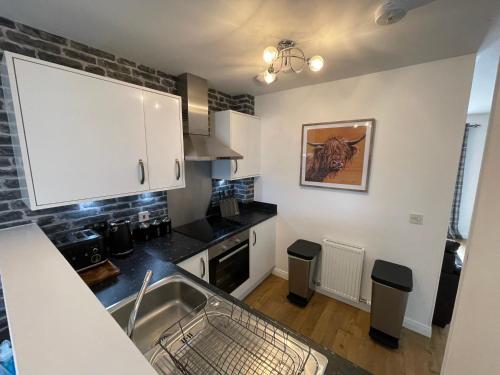 a kitchen with a sink and a counter top at Gorsebank Mews, Stylish Modern 2-Bed Townhouse with Private Garden in Inverness