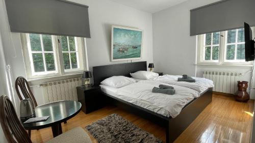 a bedroom with a bed and a table and windows at Villa ANSER in Połczyn-Zdrój