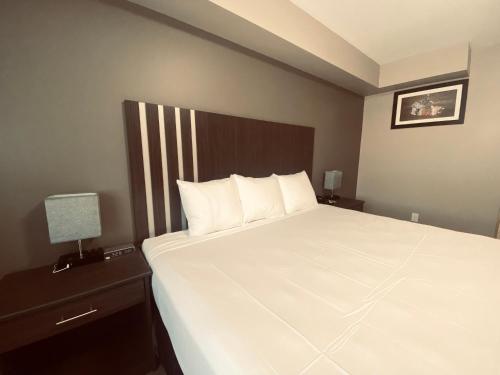 a bedroom with a large white bed with a wooden headboard at Econo Lodge in Prince George