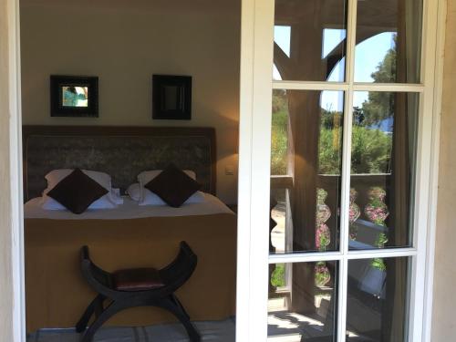 a room with a bed and a chair next to a window at Le Clos des Sept Palmiers in Cavalaire-sur-Mer