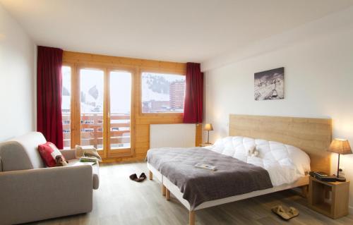 a bedroom with a bed and a chair and a couch at Résidence Odalys Le Pelvoux in La Plagne