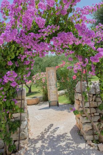a garden with pink flowers and a stone wall at Masseria Parco della Grava in Pezze di Greco