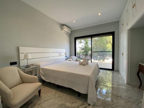 a bedroom with a bed and a chair and a window at TarracoHomes, TH142 Villa Vista Alegre in Tarragona