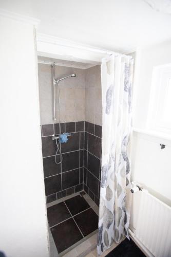 a bathroom with a shower with a shower curtain at Cozy house in the idyllic village of Haldórsvík in Haldarsvík