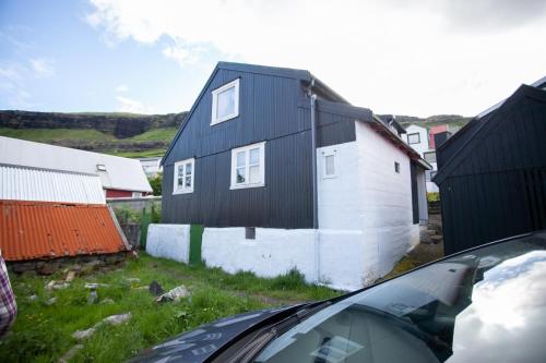 a black and white house and a car at Cozy house in the idyllic village of Haldórsvík in Haldarsvík