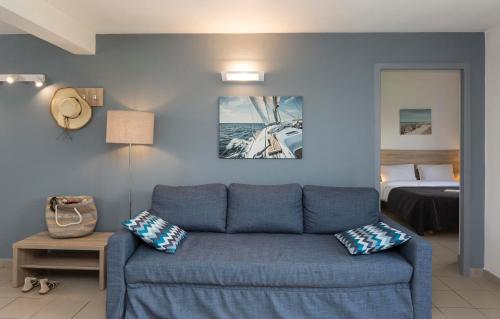 a living room with a blue couch and a bed at Résidence Odalys Le Village des Amareyeurs in Le Château-dʼOléron