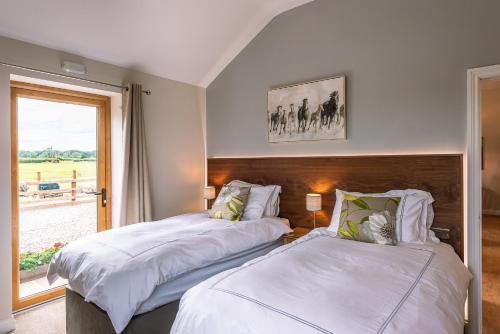 two beds in a room with a window at Brecks Farm - Cow Kennels in York