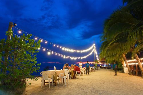 a group of people sitting at tables on the beach at night at Haad Yao Bayview Resort & Spa - SHA plus Certified in Haad Yao
