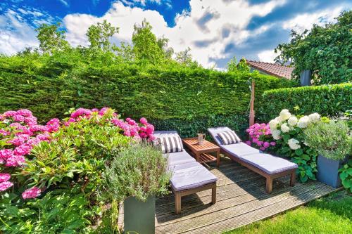 a garden with two chairs and flowers on a wooden deck at B&B Hoofddorp in Hoofddorp