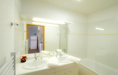 a white bathroom with a sink and a mirror at Résidence Odalys Le Buet in Morillon