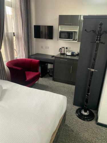 a hotel room with a bed and a red chair at Trivelles Regency, Nottingham in Nottingham