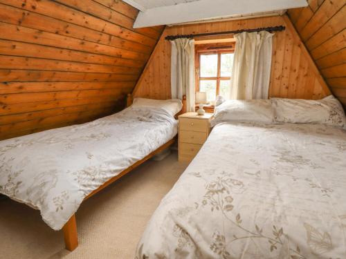 two beds in a wooden room with a window at Woldsend Cottage in Horncastle