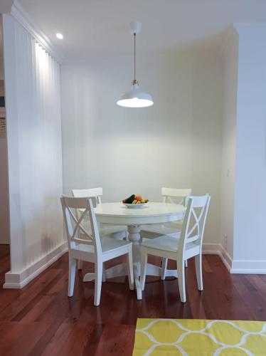 a white dining room table with four white chairs at Apartamentos Ázera - António Ázera in Praia da Vitória
