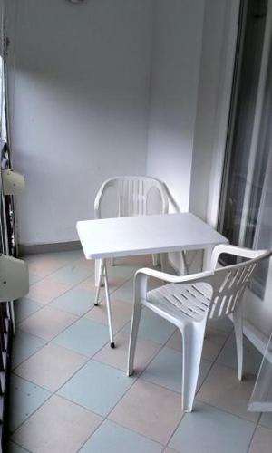 a white table and a white chair in a room at Centrum apartman in Balatonlelle