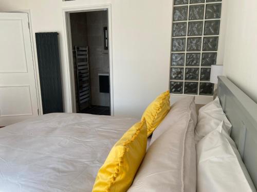 Una cama con dos almohadas amarillas encima. en Warwick House - Stunning house with terrace and sea views, sleeps 11, en Worthing