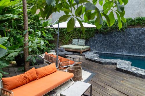 a patio with an orange couch next to a pool at Maka Hotel Boutique in Tulum