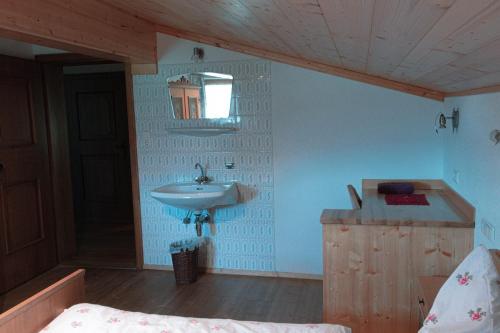 a bathroom with a sink and a mirror and a bed at Unterholzhof in Piesendorf