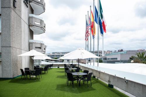 a row of tables and chairs on a balcony with flags at Hotel Palacio del Mar in Santander