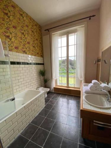 a bathroom with two sinks and a tub and a window at Chateau de Clinzeau in Saint-Léger-de-Fougeret