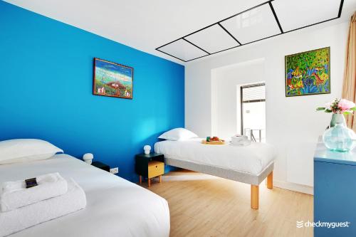 a room with two beds and a blue wall at CMG Gaite - Montparnasse in Paris