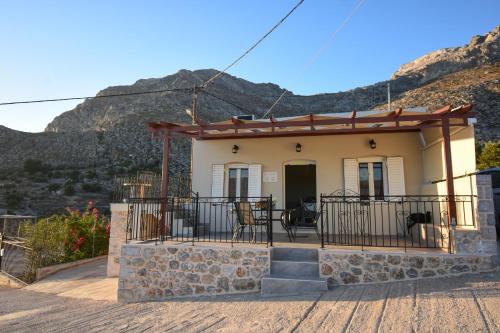 a house with a balcony with mountains in the background at Private House Niki Kalymnos in Panormos Kalymnos