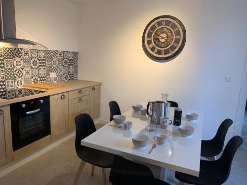 une cuisine avec une table, des chaises et une horloge murale dans l'établissement Le famillial , 2 chambres doubles lits faits et serviettes de toilette fournies Avec parking PRIVE 1 VOITURE, NETFLIX, DISNEY PLUS DISPONIBLE, à Dieppe