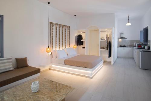 a white bedroom with a bed and a kitchen at La Belle Vie - Santorini - Adults Only in Kamari