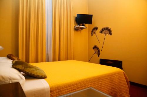 1 dormitorio con 1 cama con sábanas amarillas y flores en Hotel Damian Park Hotel Delle Magnolie en Trofarello