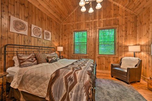 a bedroom with a bed and a chair and wooden walls at Luxury Cabin with Hot Tub about 3 Miles to Hochatown! in Broken Bow