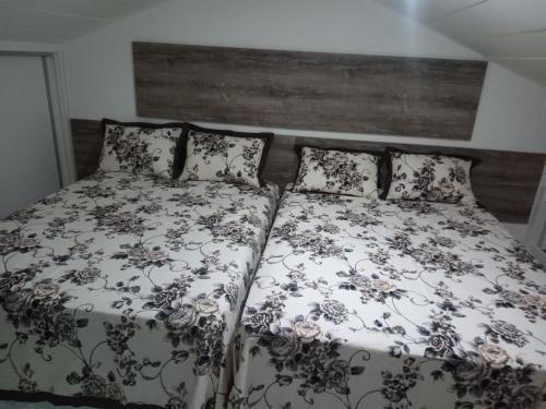 a bed with a black and white comforter and pillows at Apartamento Praia do Forte in Mata de Sao Joao