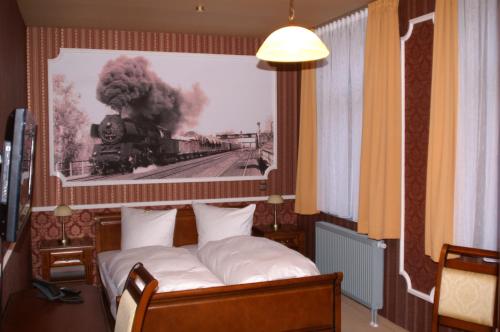a bed in a room with a picture of a train at Eisenbahnromantik Hotel in Meyenburg