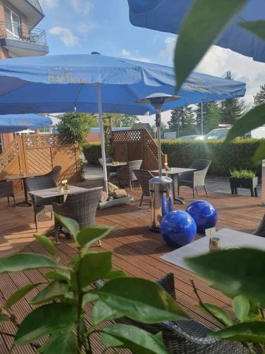 a patio with tables and chairs and blue umbrellas at Hotel Novum in Hinte