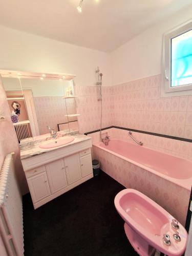 La salle de bains rose est pourvue d'un lavabo, d'une baignoire et de toilettes. dans l'établissement Puy du Fou Maison 12 personnes 4mn du Grand Parc, aux Épesses