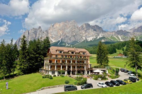 a hotel in the mountains with cars parked in a parking lot at Boutique Hotel Villa Blu Cortina D'Ampezzo in Cortina dʼAmpezzo