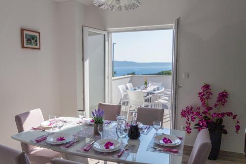 a white dining room with a table and chairs at Villa Lavanda Živogošće in Strn