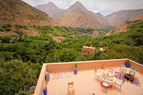 a pool with a table and chairs and mountains at Jnane Karma in Imlil