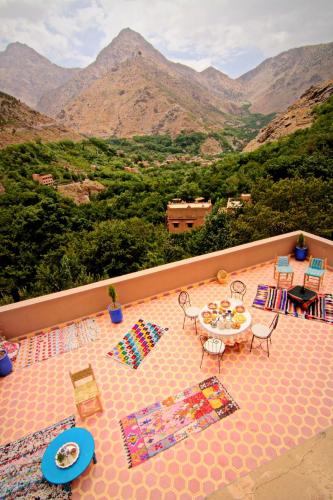 a balcony with a table and chairs and mountains at Jnane Karma in Imlil