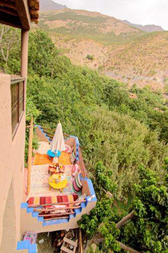 a balcony with a table with chairs and umbrellas at Jnane Karma in Imlil