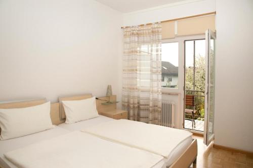 a bedroom with a white bed and a large window at Hotel Villa Martino - zum Hirsch in Bad Säckingen