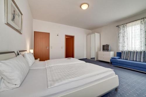 sypialnia z dużym białym łóżkiem i niebieską kanapą w obiekcie Hotel Villa Martino - zum Hirsch w mieście Bad Säckingen