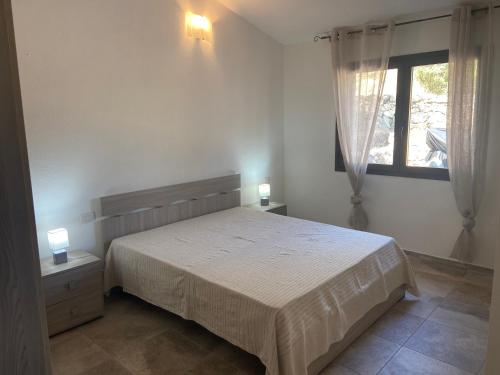 een slaapkamer met een groot bed en een raam bij Le Villette di Budoni e dintorni in Budoni